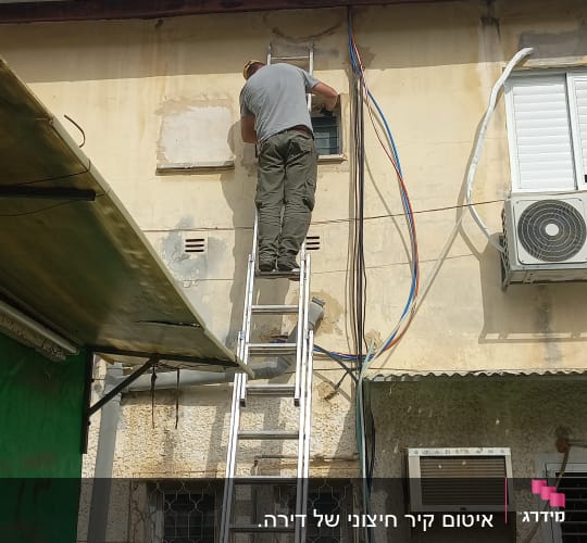 אדם על סולם אוטם קיר חיצוני של בניין